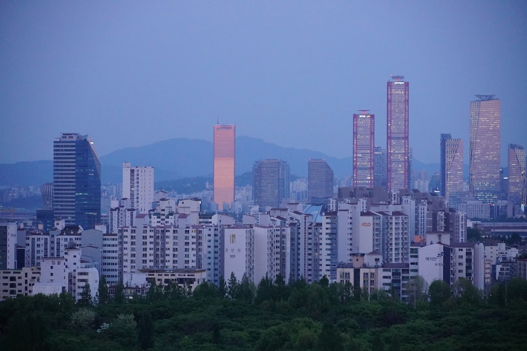Airplane flying over Korean city skyline at sunset